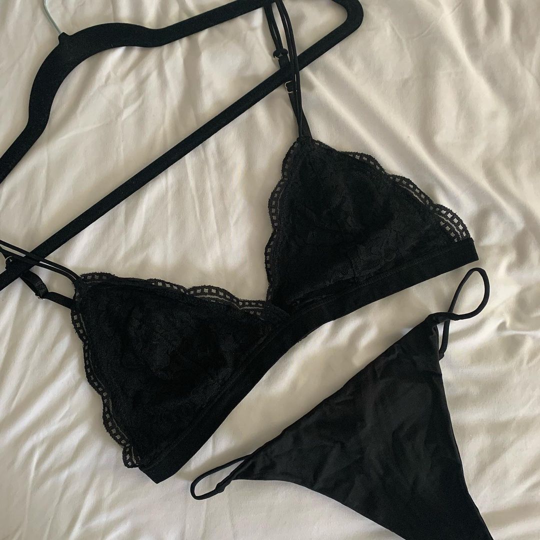 Black lace bralette and thong panty set by NKD laid on bed