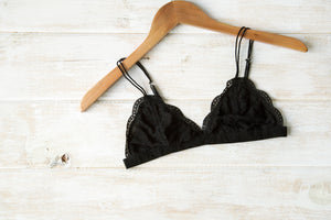 Black lace triangle bralette from NKD lingerie laid on a bed