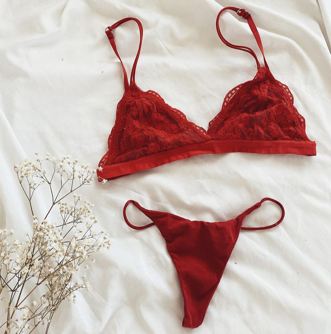 Red lace bralette and thong panty set from NKD laid out on white bedding