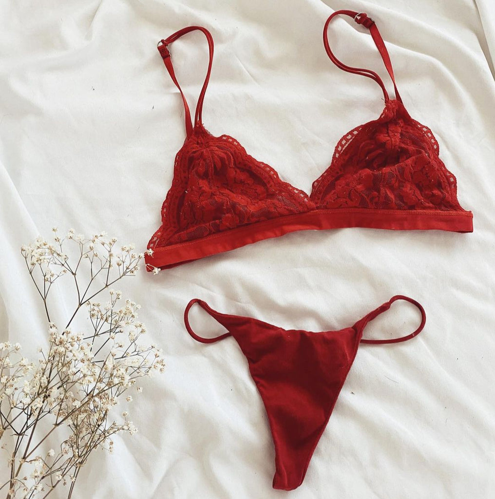 Red lace bralette and thong panty set from NKD laid out on white bedding